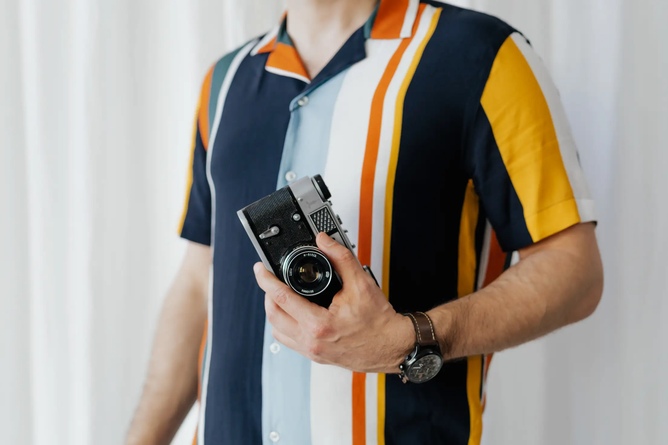 man in a colorful polo shirt with a vintage camera in his hand free photo