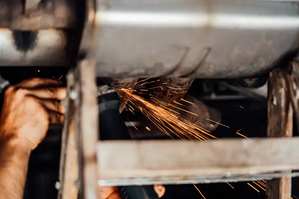 sparks from cutting an iron car part in repair shop free photo