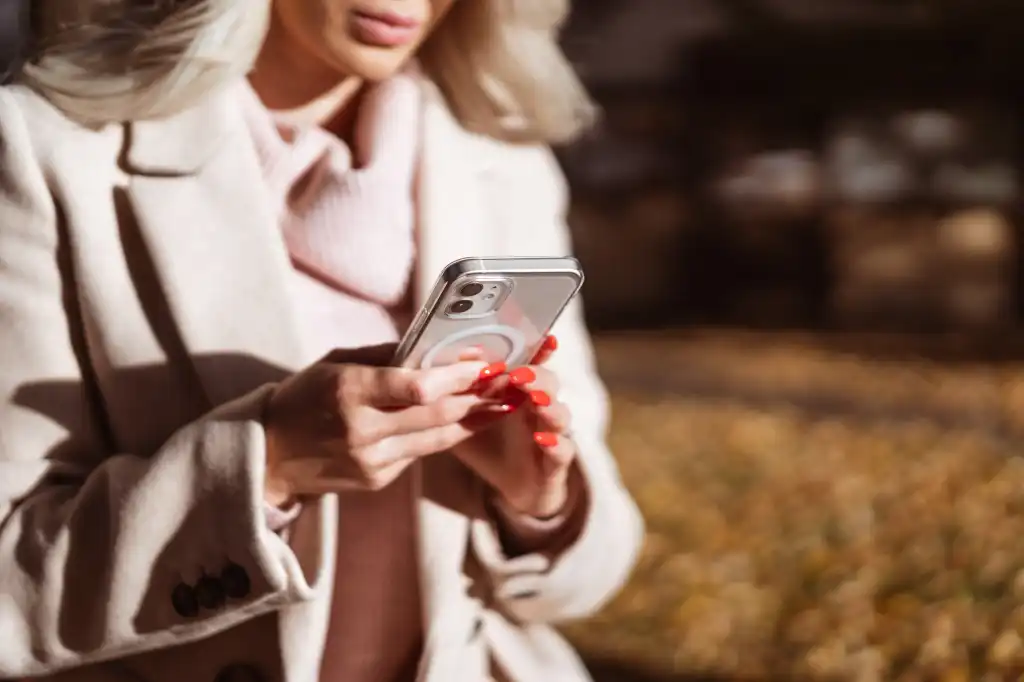 woman in beige coat using her smartphone free photo