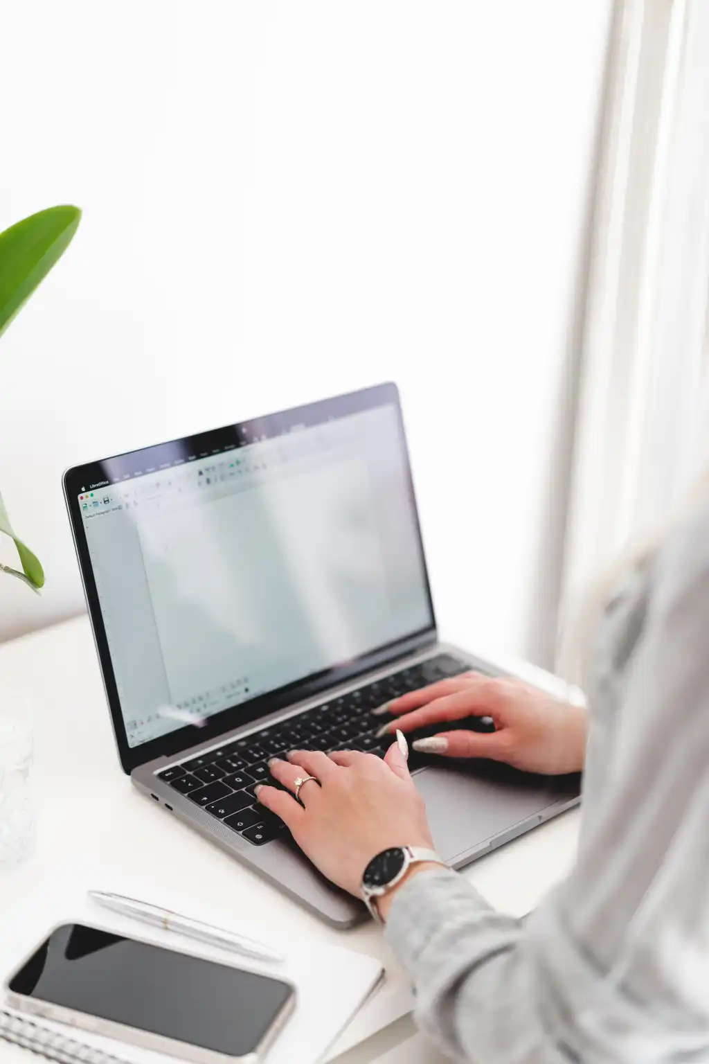 woman writing on her laptop in a bright white office free photo