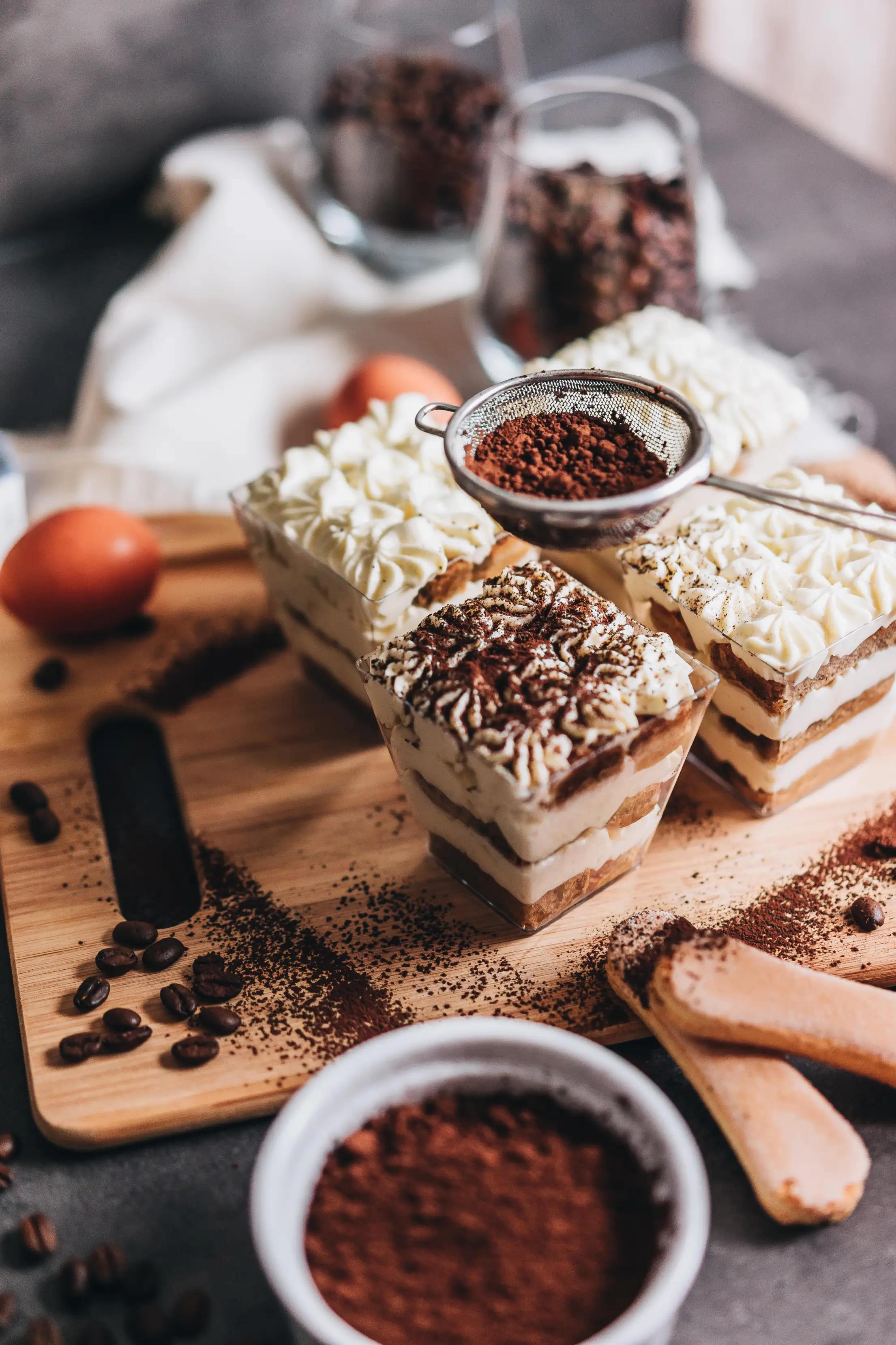 sprinkling cocoa powder on tiramisu trifles