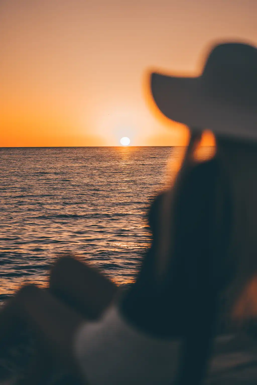 woman in a hat looking at sunset above the sea free photo