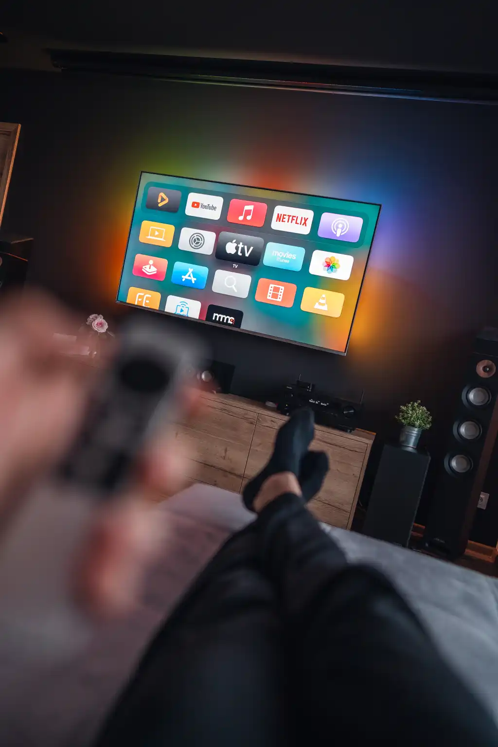 man is lying on a sofa and watching movies on apple tv free photo